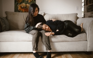Two women on a couch, one comforting the other