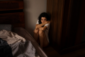 A sad woman sitting in a corner of a room before getting sex addiction treatment in Idaho