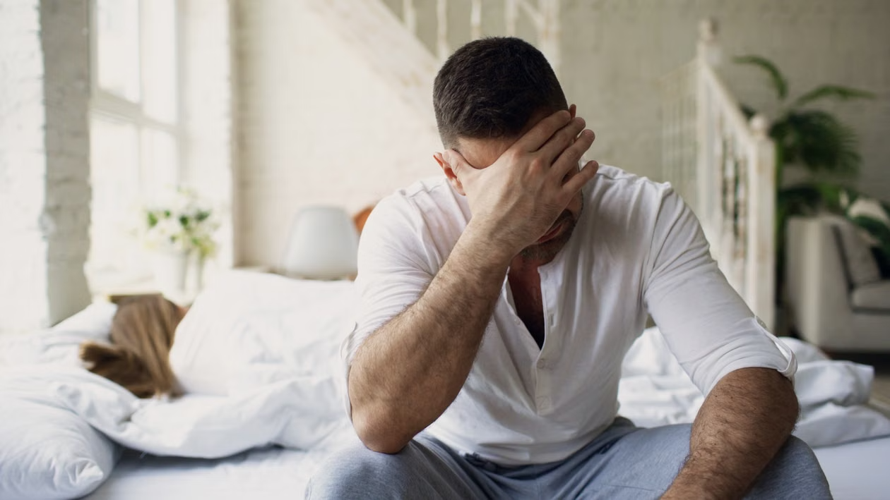 Man sitting on a bed appearing distressed while considering inpatient treatment for sex addiction in Idaho.