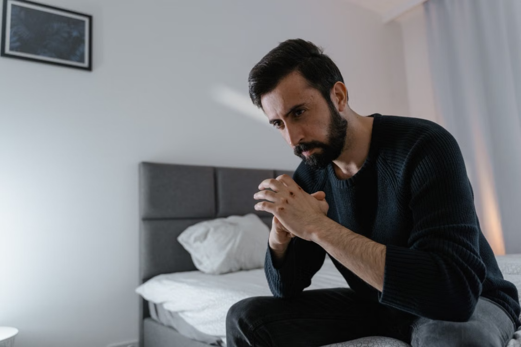 Man sitting on a bed and reflecting on choosing an inpatient sexual addiction treatment center in Idaho.